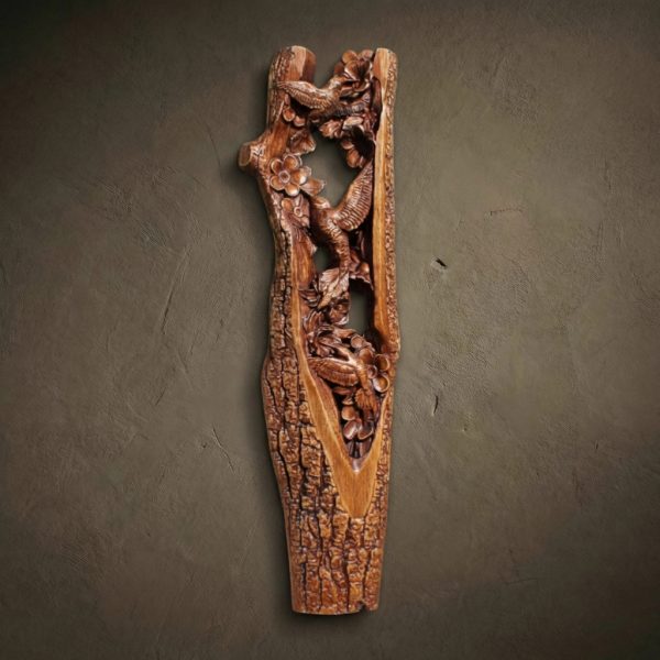 Custom hand-carved Iroko wood vertical sculpture of Hummingbirds and flowers. This intricate wildlife carving features several hummingbirds in flight, hovering around blooming flowers inside a textured, bark-covered hollow of a tree. The delicate wing details and floral petals are finished with natural oil to highlight the rich, warm wood grain. A premier example of bespoke bird-themed wall art and luxury decorative wood carvings.