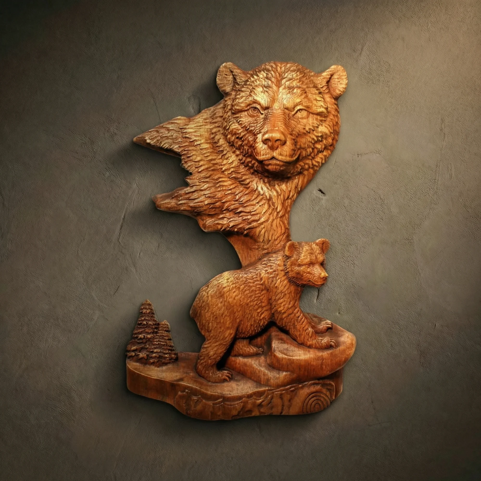 Custom hand-carved Iroko wood sculpture of a Grizzly Bear and cub. This vertical wildlife carving features a large, detailed head of a mother bear with a protective gaze, set above a small cub walking across a rocky ledge. The composition includes a miniature pine tree and is finished with natural oil to highlight the thick fur textures and deep wood grain. A premier example of bespoke bear-themed wall art and custom-made forest wildlife sculptures.